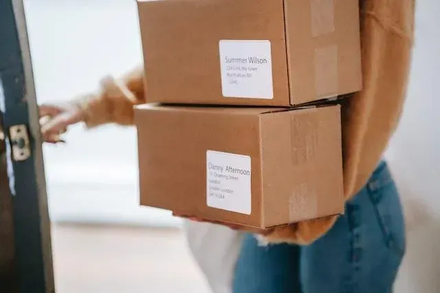 Person carrying two labelled cardboard parcels
