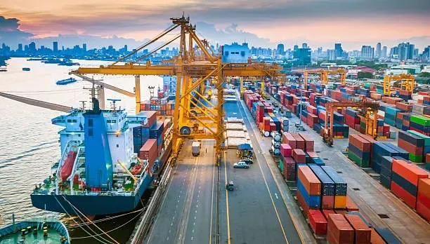 Container ship being loaded beside stacks of containers at a port