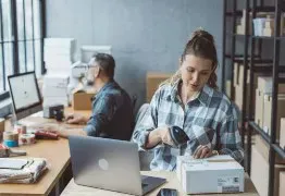 Small business owner preparing a parcel beside a laptop