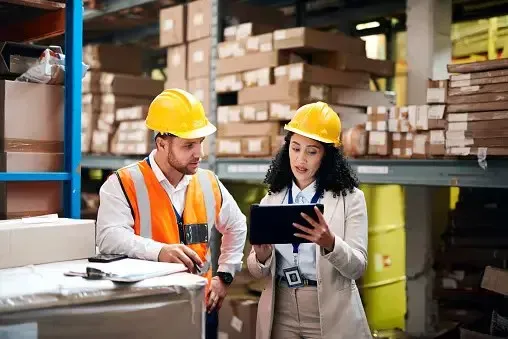 Two warehouse staff reviewing information on a tablet