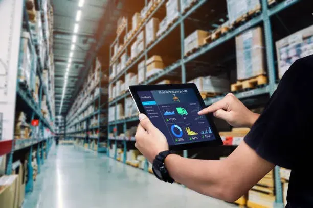 Warehouse worker reviewing charts on a tablet between storage racks