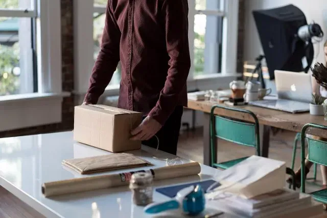 Person preparing a cardboard parcel at a packing table