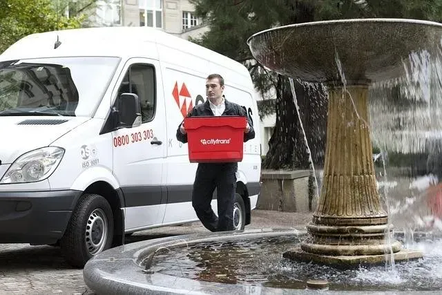 Courier carrying a delivery bag beside a parked van