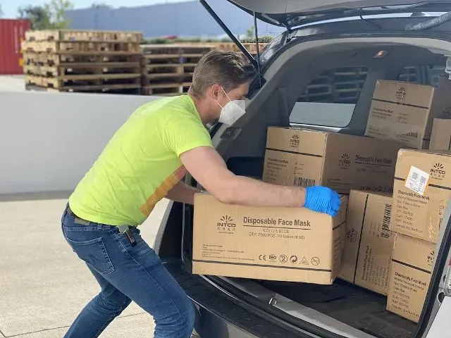 Worker loading cardboard boxes into the back of a vehicle