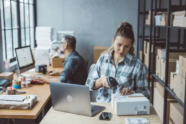 Small business owner preparing a parcel beside a laptop
