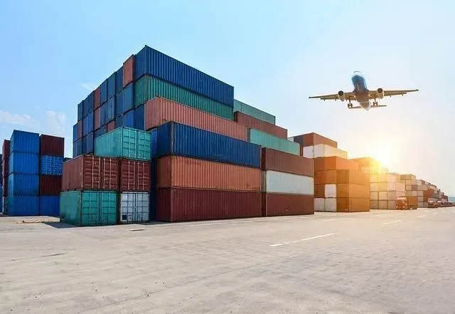 Stacked shipping containers with an aircraft flying overhead