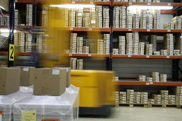 Warehouse shelves filled with boxed stock and packages in the foreground