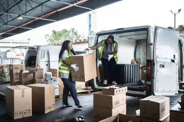 Delivery workers loading parcels into a van at a warehouse