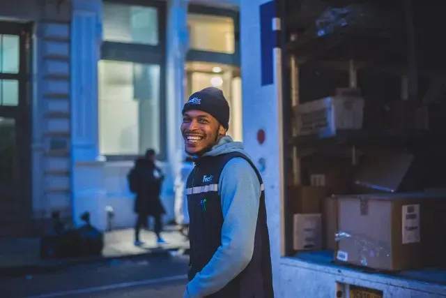 Delivery worker standing beside an open truck filled with parcels
